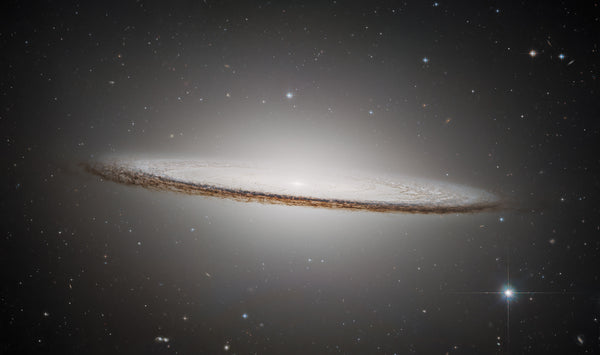 Sombrero Galaxy photographed by Hubble — glowing bulge and dark dust lane 
against deep space, ESA/Hubble & NASA